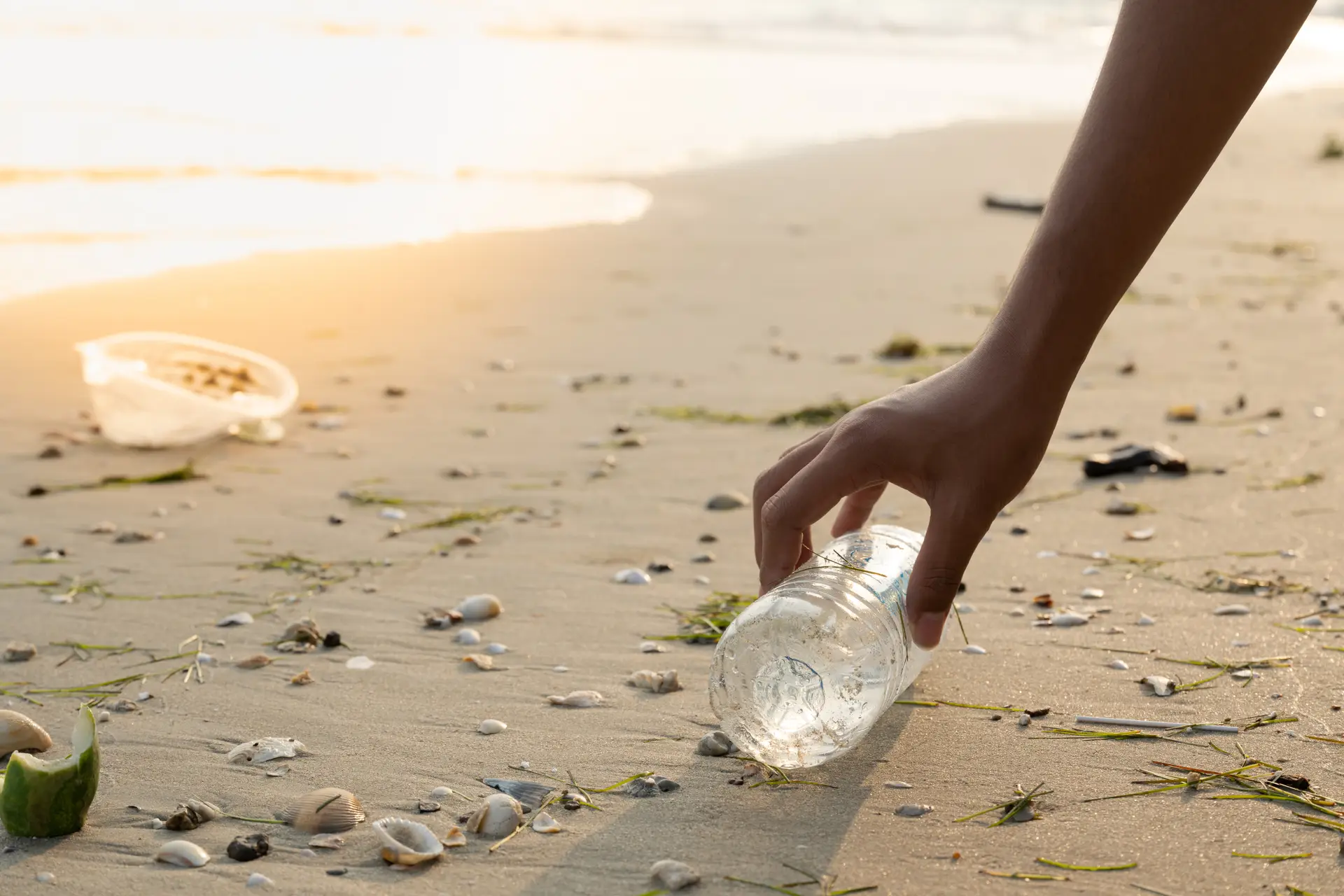 Close up hand keeping plastic bottle on the sand beach.Save the earth.Environment ecology care and renewable concept.Volunteer or traveller collecting plastic waste.Cleaning beach on morning time. Close up hand keeping plastic bottle on the sand beach.Save the earth.Environment ecology care and renewable concept.Volunteer or traveller collecting plastic waste.Cleaning beach on morning time.
