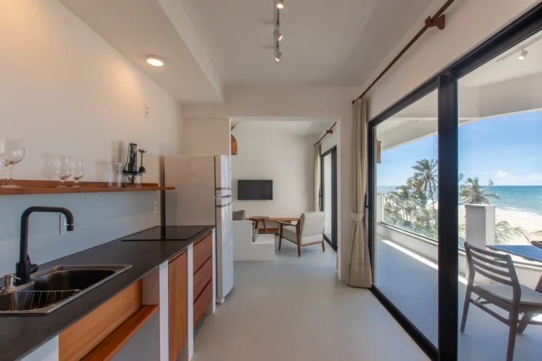 Kitchen of a two-bedroom apartment in Cumbuco looking through the dining area to the balcony and the sea beyond