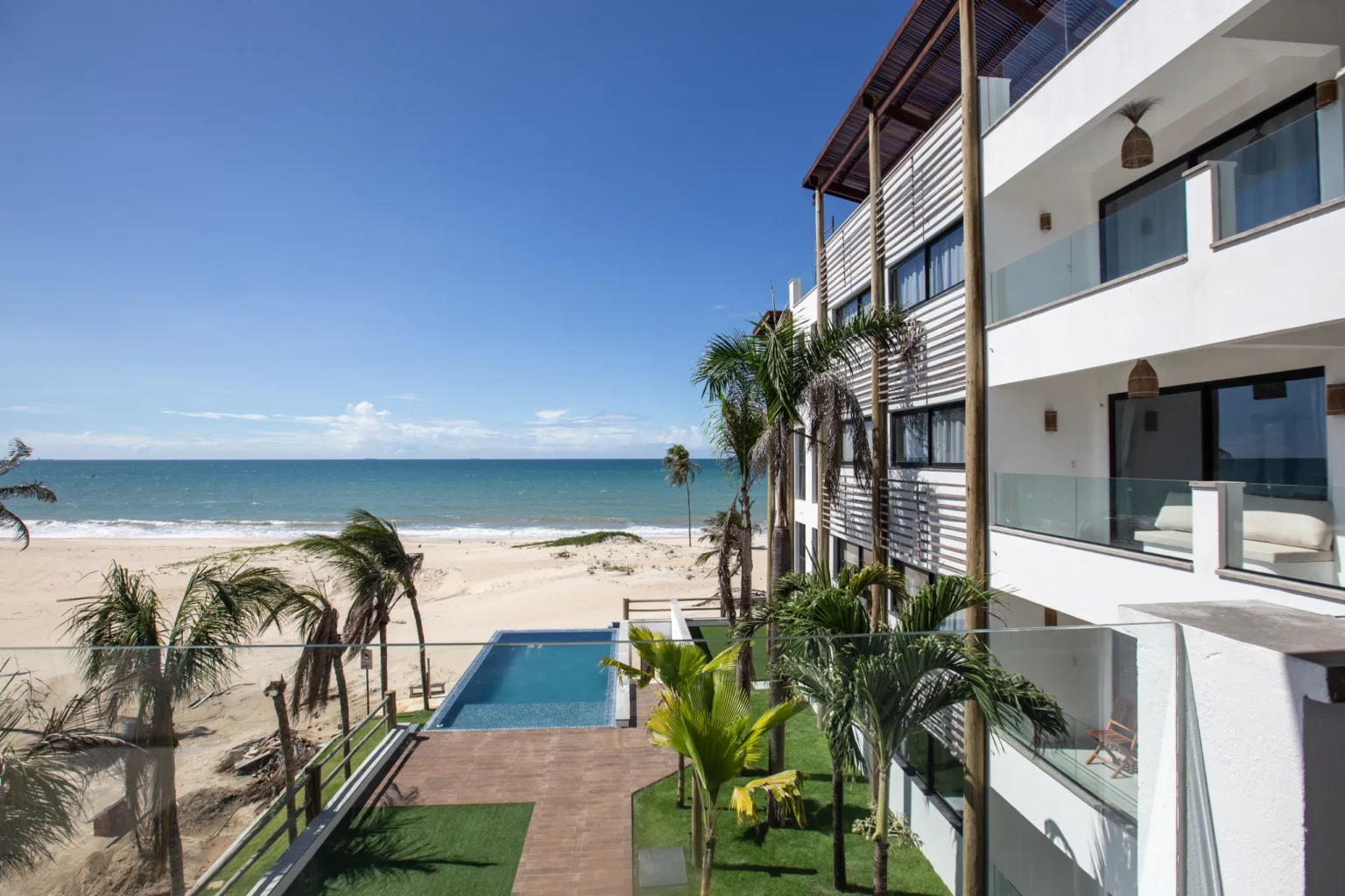 View from the apartments at Windtown Cumbuco over the swimming pool, the palm trees and the white sand to the Atlantic