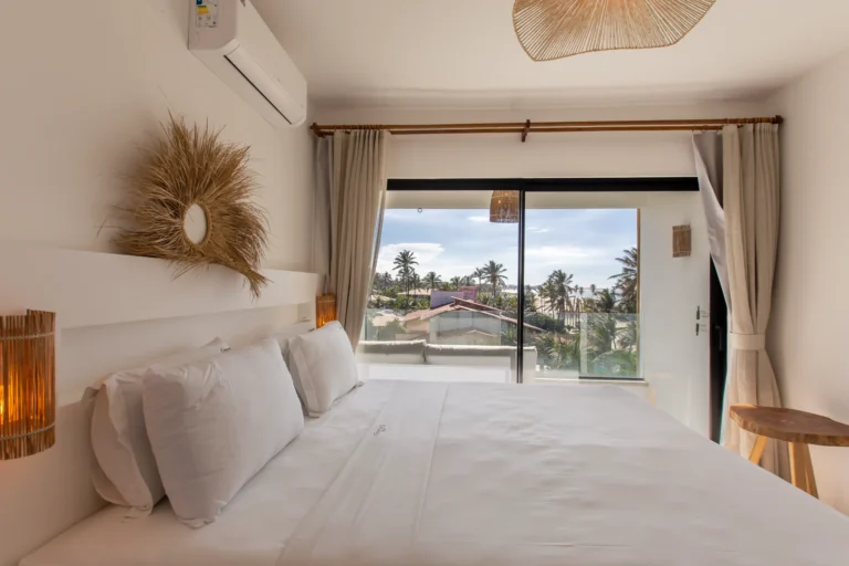 Bedroom of a one-bedroom apartment at Windtown Cumbuco with a double bed and sliding doors opening onto the terrace and the beach