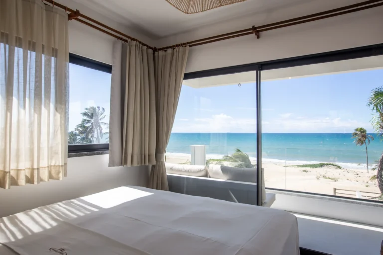 Sea-view bedroom in a two-bedroom beachfront apartment at Windtown Cumbuco, with a full-height window onto the beach