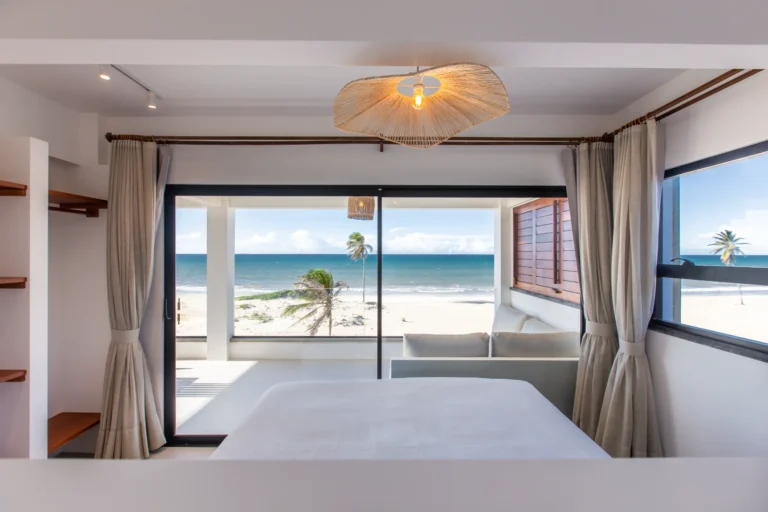 Three-bedroom apartment living space at Windtown Cumbuco with rattan pendant lighting and sliding doors onto the sea-facing terrace